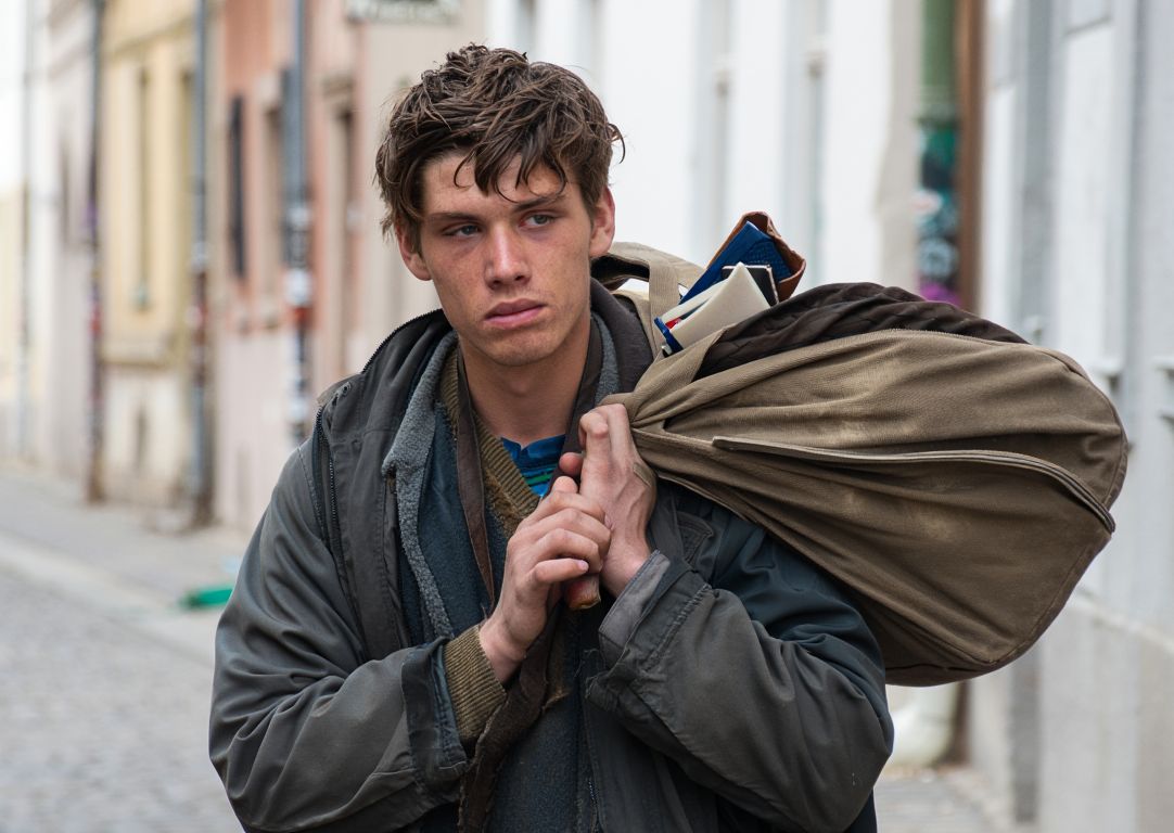 Грустный мужчина стоит на улице с мешком вещей